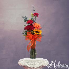 Tall mixed bouquet in a glass vase with a large orange ribbon