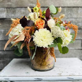 Mixed floral arrangement in a glass vase with orange and white blooms