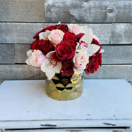 Bouquet of red, pink, and white roses in a gold vase