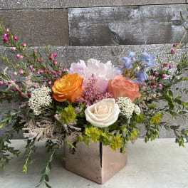 Mixed bouquet with roses and pastel blooms in a square vase