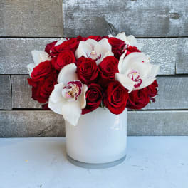 Red roses and white orchids arranged in a white vase