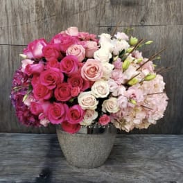 Pink and white roses with pale hydrangeas in a gray vase