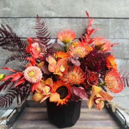 Orange and red floral arrangement in a black vase