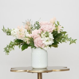Pink roses and white flowers arranged in a white vase