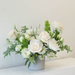 White rose arrangement in a gray vase with green accents