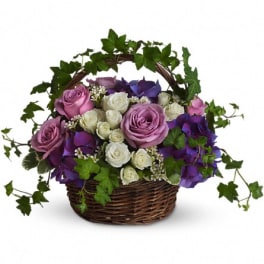 Basket arrangement of pink and white roses with purple flowers
