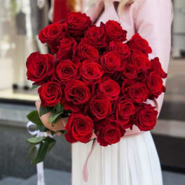 Large bouquet of red roses held by a person in a light dress