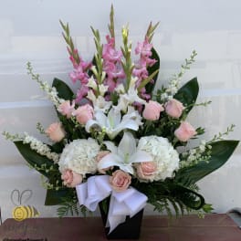 Pink and white floral arrangement in a black vase with a white ribbon
