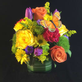Colorful mixed bouquet in a green vase with a butterfly accent