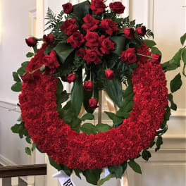 Red rose and carnation funeral wreath on an easel