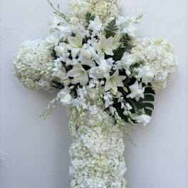 White floral cross arrangement on an easel