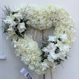 White floral heart wreath on an easel with ribbon