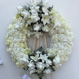 White floral funeral wreath on a wooden easel