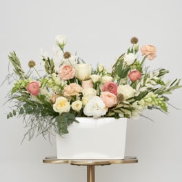 Mixed pastel flowers arranged in a white rectangular vase
