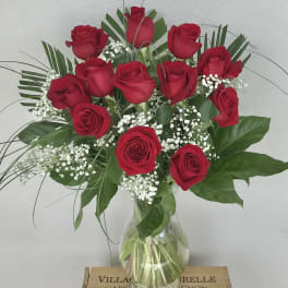 Red roses arranged in a clear glass vase with baby's breath