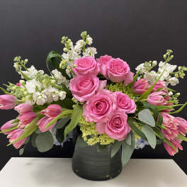 Pink roses and tulips arranged in a black vase