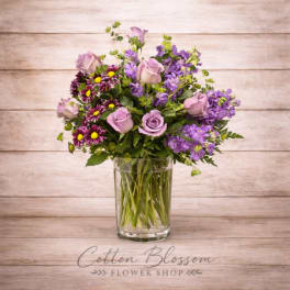 Lavender roses and purple mixed flowers in a clear glass vase