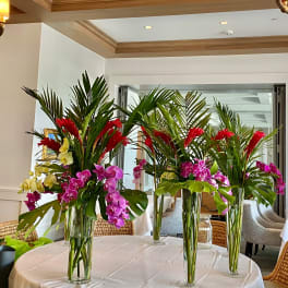 Tall tropical floral centerpieces with orchids and red blooms in glass vases