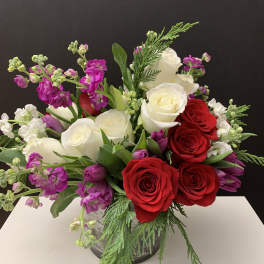 Bouquet of red and white roses with purple blooms in a vase