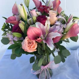 Bouquet of pink lilies, roses, and calla lilies in a glass vase