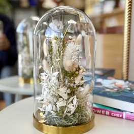 Dried floral arrangement under a glass dome with a gold base