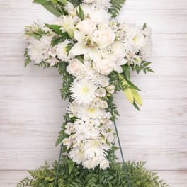 White floral cross arrangement with lilies, roses, and chrysanthemums