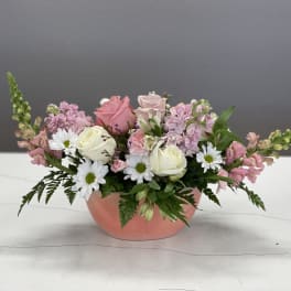 Pink and white flower arrangement in a peach bowl vase