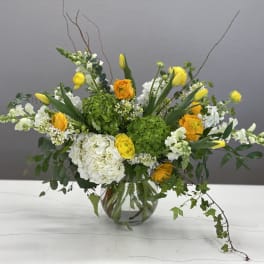 Yellow and white mixed flower arrangement in a clear glass vase