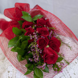 Bouquet of red roses with small purple flowers wrapped in red mesh