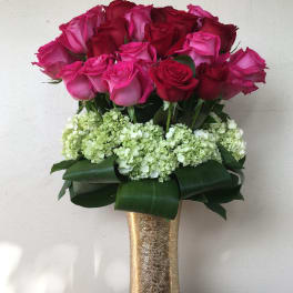 Bouquet of pink and red roses in a gold vase with white hydrangeas