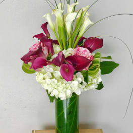 Pink and white calla lily arrangement in a tall glass vase