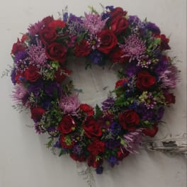 Heart-shaped floral wreath with red roses and purple flowers