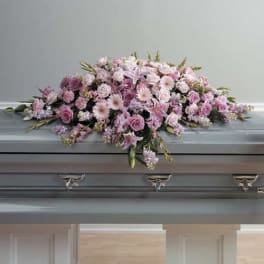 Pink and white floral casket spray on a gray coffin