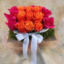 Bouquet of orange and hot pink roses with a white ribbon