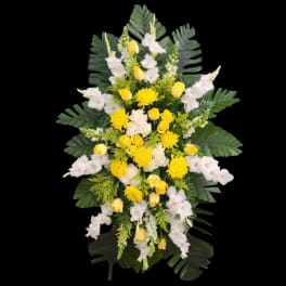 Yellow and white floral standing spray with large tropical leaves