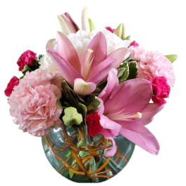 Pink lilies and carnations arranged in a glass vase