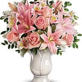 Pink roses and lilies arranged in a white vase