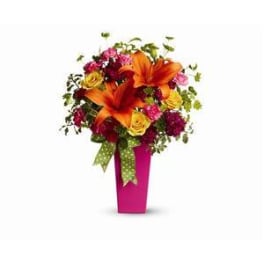 Bouquet of orange lilies and mixed flowers in a pink vase with ribbon