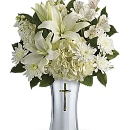 White lilies and daisies in a silver vase with a cross