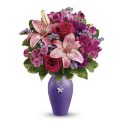 Pink lilies and roses in a purple vase with a butterfly necklace
