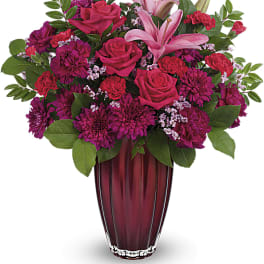 Pink and magenta flower arrangement in a red glass vase