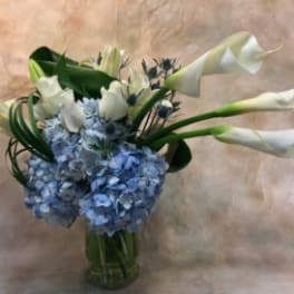 Blue hydrangeas and white calla lilies in a glass vase