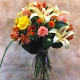 Bouquet of lilies, roses, and orange flowers in a glass vase