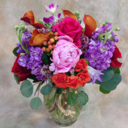 Mixed bouquet of pink, purple, orange, and red flowers in a glass vase