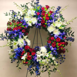 Large circular wreath of red, white, blue, and purple flowers on a stand
