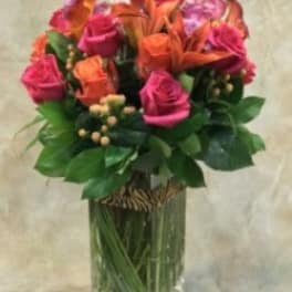 Bouquet of pink and orange flowers in a tall glass vase