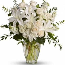 White lilies and roses arranged in a clear glass vase