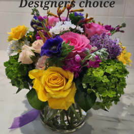 Mixed bouquet of roses, hydrangeas, and purple blooms in a glass vase