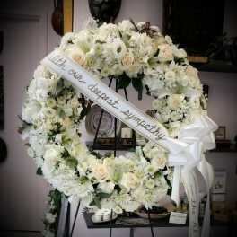 Large white sympathy wreath with a ribbon on a stand
