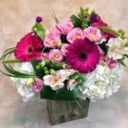 Pink and white mixed flower arrangement in a clear square vase